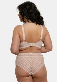 Soutien-gorge en dentelle beige et culotte taille haute, présentant des motifs géométriques et des bords festonnés, avec des bretelles réglables et une fermeture à crochet à l'arrière.