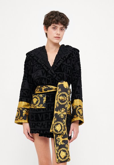 Robe noire avec un motif de logo en relief, des manches rehaussées d'or et une ceinture décorative mettant en valeur des motifs intricats.