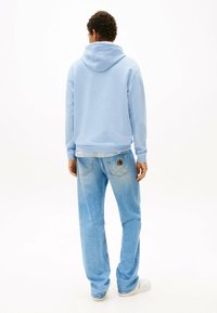 Felpa leggera blu con tasca a marsupio, polsini a coste, abbinata a jeans in denim blu chiaro a vestibilità ampia con logo ricamato.