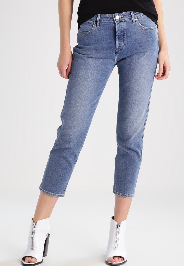 Ljust blå denimjeans med rak passform, fem fickor och medelhög midja, ihopparade med vita dragkedjeskor med klack.