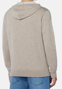 Beige hoodie med texturerad stickning, justerbar huva och ribbade ärmslut. Bakvy med rak nederkant och avslappnad passform.