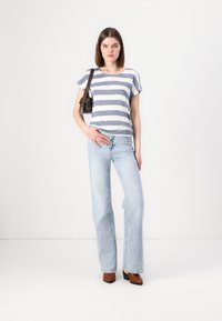 Stripet kortermet skjorte i hvit og blå, lyse blå utvidede jeans, brune hælbooties, liten brun håndveske med stropper.