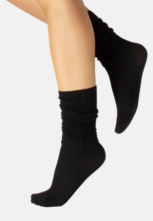 Schwarze gerippte Socken mit einem lässigen Design, die eine weiche Textur und einen enganliegenden Knöchel haben, ideal für den Alltag.