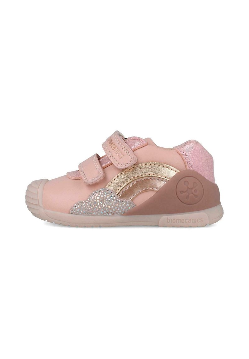 Zapatilla deportiva infantil rosa con dos correas de velcro, acentos plateados brillantes, suela de goma texturizada y un respaldo acolchado para mayor soporte.