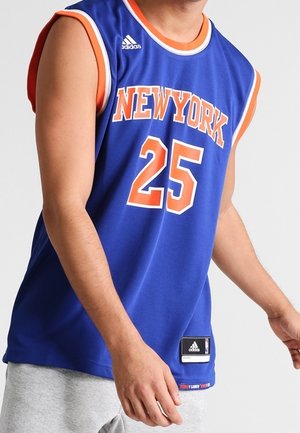 Niebieska koszulk bezrękawnikowa New York z pomarańczowym obszyciem, numer 25, logo Adidas, noszona przez osobę o jasnej karnacji i krótkich rękawach.
