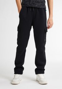 Zwarte katoenen joggingbroek heeft een relaxed fit, een elastische tailleband met trekkoord, zijvakjes en een gestructureerde logopatch op het been.