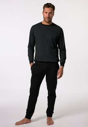 Chemise noire à rayures côtelées à manches longues avec un col rond, associée à un pantalon noir fuselé. L'ensemble présente des poignets ajustés et une coupe décontractée.