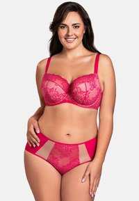 Lys pink lingerisæt med en blonde-BH med vattering og gennemsigtige paneler, kombineret med matchende højtaljede trusser med blomstermotiv.