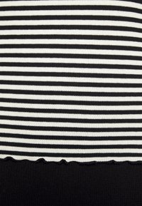 Zwart-wit gestreepte stof met geribbelde textuur, met een golvende zoom die overgaat in een effen zwarte stof aan de onderkant.