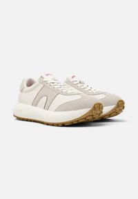 Světlé šedé semišové a kožené tenisky s kulatými bílými podrážkami, s robustním designem a decentním značením na patě a jazyku.