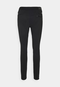 Black skinny jeans with a smooth texture, featuring two back pockets and a sleek design. No visible brand logo on the back.