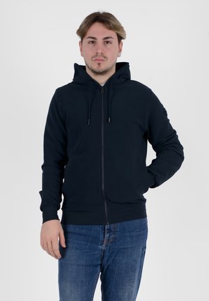 Felpa con zip di colore navy, dotata di cappuccio regolabile con cordino, polsini e vita a coste. Realizzata in tessuto morbido, abbinata a jeans in denim blu. Design semplice.
