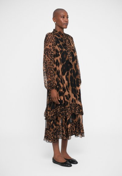 Abito midi in tessuto trasparente con stampa leopardata, caratterizzato da un collo alto, maniche lunghe, strati arricciati e una silhouette fluida. Scarpe nere piatte.
