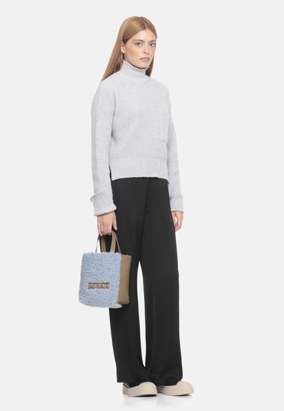 Maglione grigio a collo alto in maglia con texture a costine, abbinato a pantaloni neri a gamba larga e una borsa blu pelosa con una tracolla color nocciola e logo.