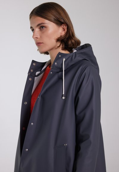 Marineblå vandtæt jakke med hætte, trykknapper, snoretræk og sidelommer. Fremstillet af glat, holdbart materiale med en afslappet pasform.