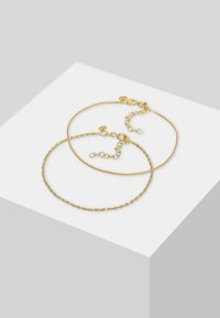 Set med två guldarmband. Det ena har en slät, polerad kedja; det andra har en vriden design. Båda har justerbara lås.