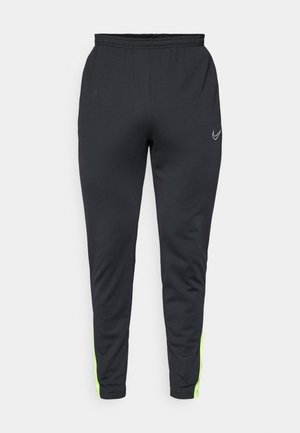 Pantalon de sport noir avec un design fuselé, une taille élastique et des accents vert fluo sur les côtés. Fabriqué en matériau lisse et léger.