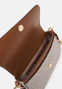 Beige patterned handbag with brown leather interior, magnetic gold clasp, and small inner pocket, open showing lining and stitching details.