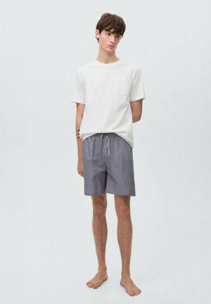 T-shirt en coton blanc avec une poche, associé à un short rayé bleu marine et blanc. Le short dispose d'une taille élastique et d'un cordon de serrage.