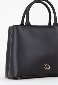 Borsa a mano in pelle nera con forma strutturata, due manici superiori e accento in oro del logo. Texture liscia con angoli arrotondati e hardware minimale.