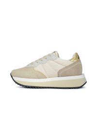Sneaker beige con pannelli in suede e rete, dotate di una spessa suola bianca, un accento dorato sul tallone e lacci grigi.