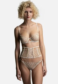 Spitzen-Bralette und passender Tanga mit einem strukturierten Spitzen-Corsage. Beige Farbe, filigranes Blumenmuster sowie verstellbare Träger und Schnürdetails.