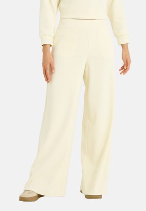 Pantalones de pierna ancha hechos de tela suave y texturizada en un color crema claro. Presentan una cintura alta y un ajuste relajado sin cierres visibles.