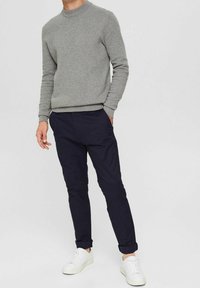 Šedý pletený svetr s kulatým výstřihem, zkombinovaný s námořnickými úzkými kalhotami a bílými teniskami. Svetr má žebrované manžety a lem.