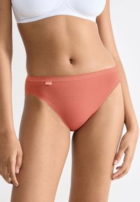 Damedragter i koralfarve lavet af glat stof med sømløst design og en lille label foran på linningen.