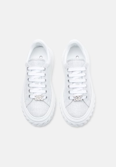 Λευκά αθλητικά παπούτσια από υφασμάτινη υφή, με χαμηλό προφίλ, στρογγυλή μύτη, λευκά κορδόνια και λαμπερή λεπτομέρεια στην περιοχή των κορδονιών.