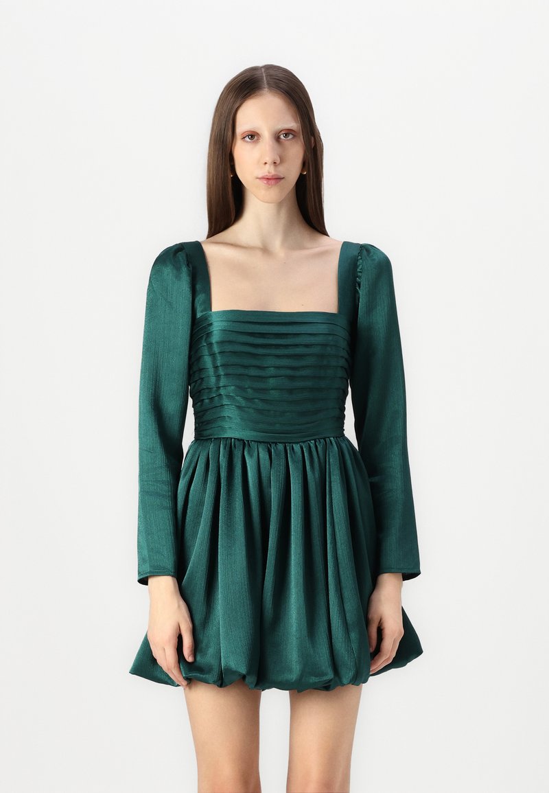 Emeraldgrön klänning i texturerad tyg. Har rsquare neckline, långa puffärmar och en veckad A-linje kjol.