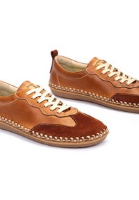 Zapatos de cuero y ante marrón presentan un diseño cosido, cordones beige y una suela flexible con un borde texturizado para mayor agarre.