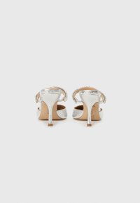 Silver high-heeled sandals with a metallic finish, adjustable ankle strap, and a textured accent along the strap.