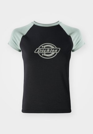 Camiseta negra con mangas raglán verde claro. Presenta un logo circular central con el texto "Dickies" en un diseño de cuerda. Textura de tela suave.