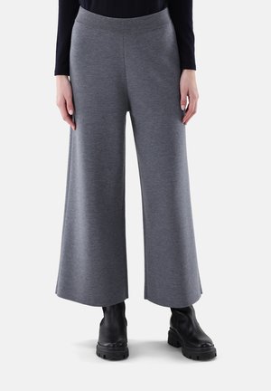Graue weitgeschnittene Hose aus weichem Stoff, mit hohem Bund und glatter Textur. Getragen mit schwarzen Ankle Boots.