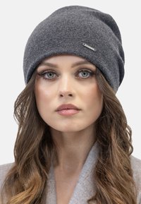 Grå strikket hue i et blødt, strækbart materiale med et slouchy design. Har et lille sølvlogo som accent foran.