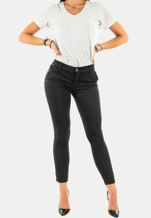 Jeans skinny negros con una textura suave y diseño de cinco bolsillos, combinados con una camiseta de cuello en V gris claro. Adecuados para un look casual.