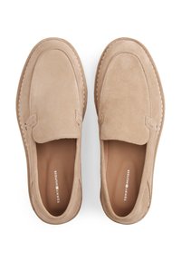 Μπεζ σουέτ παπούτσια χωρίς κορδόνια με στρογγυλεμένη μύτη, διακοσμητικές ραφές και ομαλή εσωτερική επένδυση. Χωρίς ορατά λογότυπα ή διακοσμητικά στοιχεία.