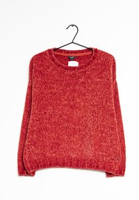 Red, textured knit sweater with a crew neckline and long sleeves. Hem features slight side slits. Hangs on a black hook against a white background.