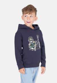 Marinblå hoodie med en grafik av en karaktär på en cykel. Tillverkad av mjukt material, med en känguruficka och ribbade muddar. Klassisk passform.