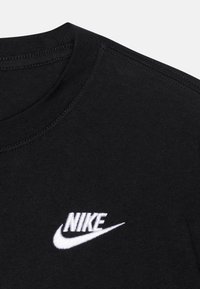 Camiseta de algodón negra con cuello redondo. Presenta un logo de Nike bordado en blanco en el pecho. Textura suave, diseño de mangas cortas.