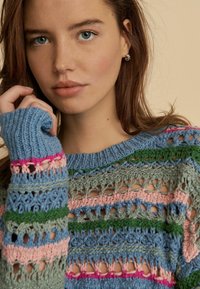 Pulover tricotat cu dungi orizontale multicolore în nuanțe de albastru, verde, roz și gri, având un design cu model deschis și texturat și guler elastic.
