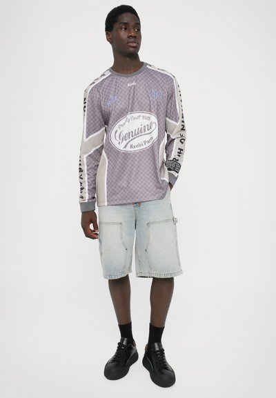 Langarmpige, grijs geblokte overhemd met de opdruk "Genuine Ksubi Park" en contrasterende mouwen, gecombineerd met lichtblauwe cargoshorts en zwarte sneakers.