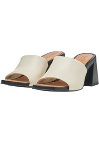 Sandali aperti davanti in crema con una fascia larga, un tacco geometrico nero e una finitura in pelle liscia. Soletta marrone visibile.