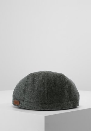 Donkergrijze wollen platte pet met stiksel details en een klein bruin leren merklabel geplaatst op een witte ondergrond tegen een grijze achtergrond.
