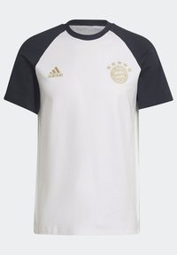 Bílý tričko s černými raglánovými rukávy. Obsahuje zlaté logo Adidas a emblém Bayernu Mnichov s pěti hvězdami. Materiál z bavlny, design s kulatým výstřihem.