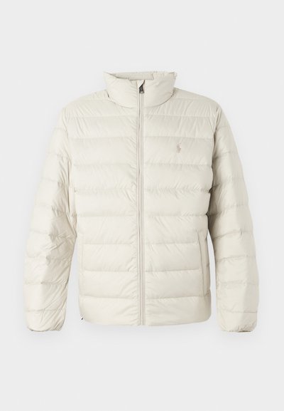 Casaco puffer bege com textura de matelassê vertical, gola alta e fecho com zipper. Apresenta um pequeno logótipo no peito e punhos elásticos.