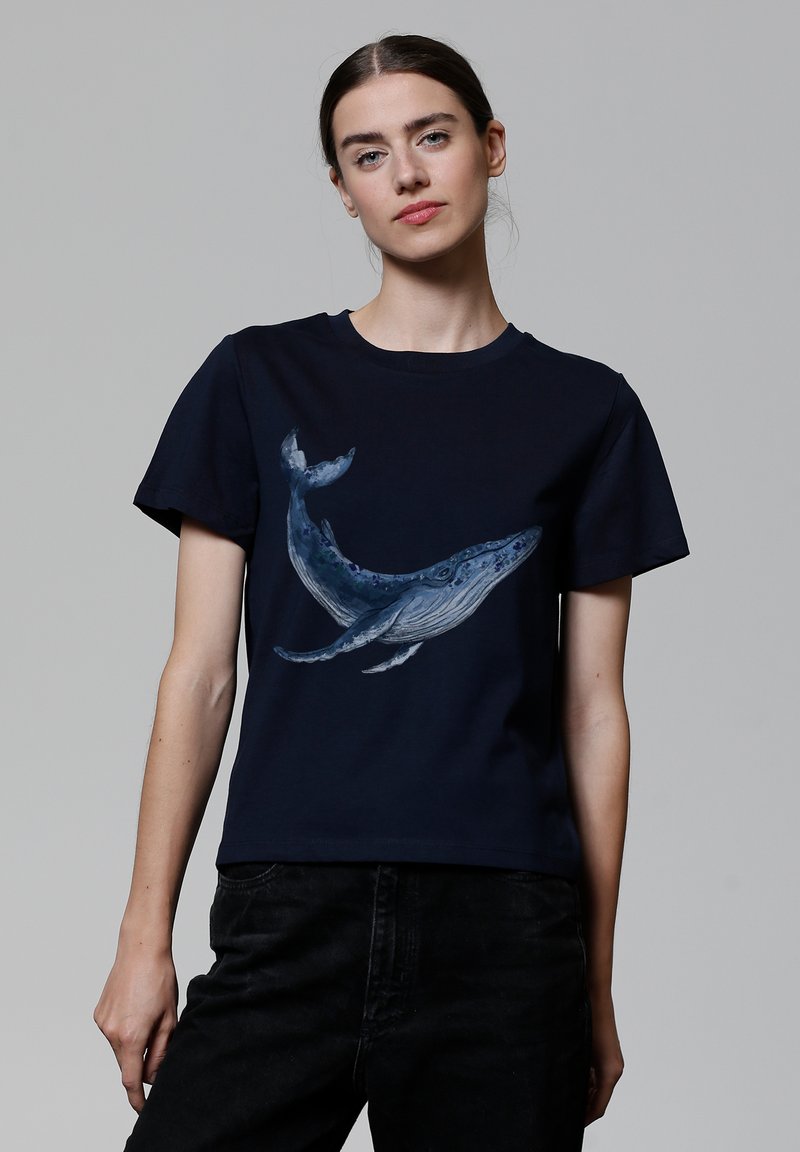 T-shirt en coton marine avec un grand graphique de baleine détaillé dans des nuances de bleu et de gris. Manches courtes et design classique à col rond.
