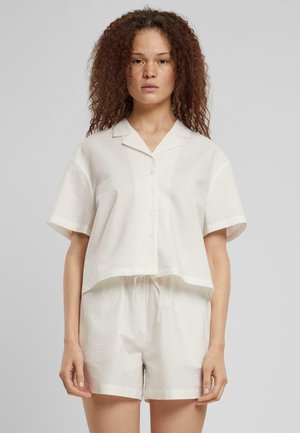 Kortermet, krageformet hvit skjorte med teksturert stoff, knapplukking, kombinert med matchende shorts med elastisk midje.