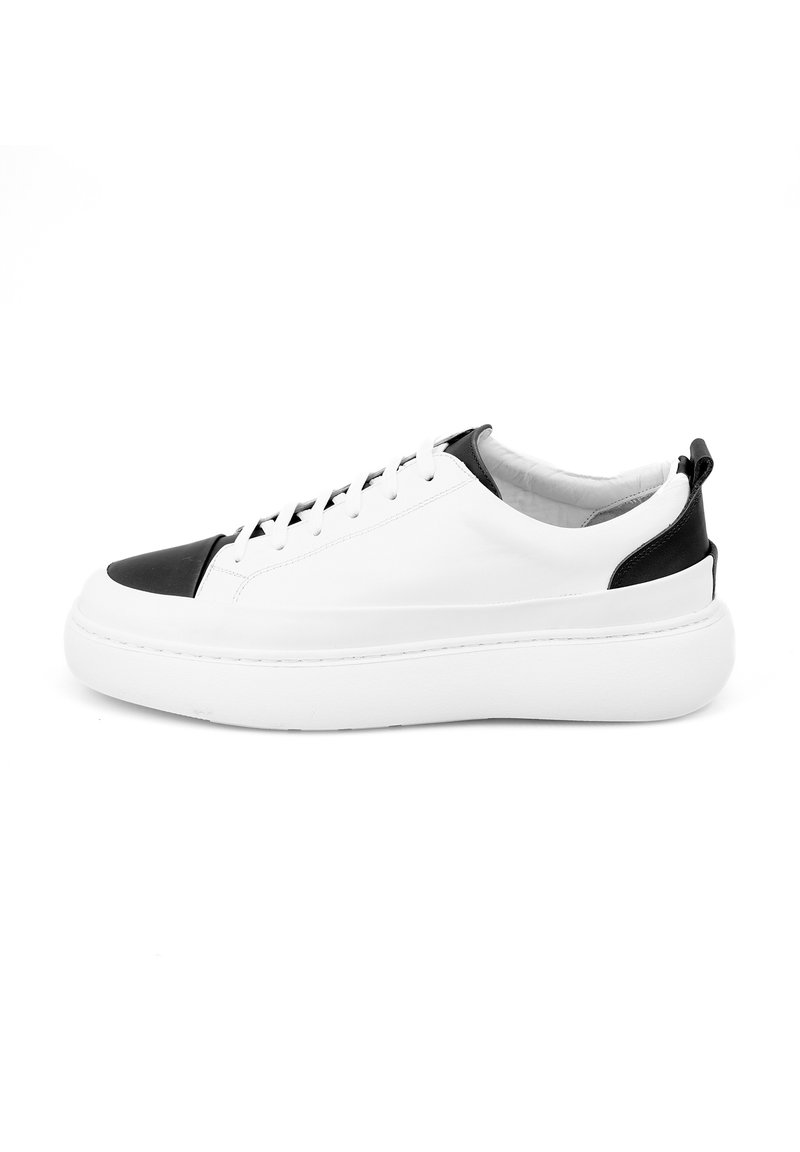 Witte leren sneaker met zwarte accenten, ronde neus, dikke witte zool en vetersluiting. Soepele textuur met minimale details.